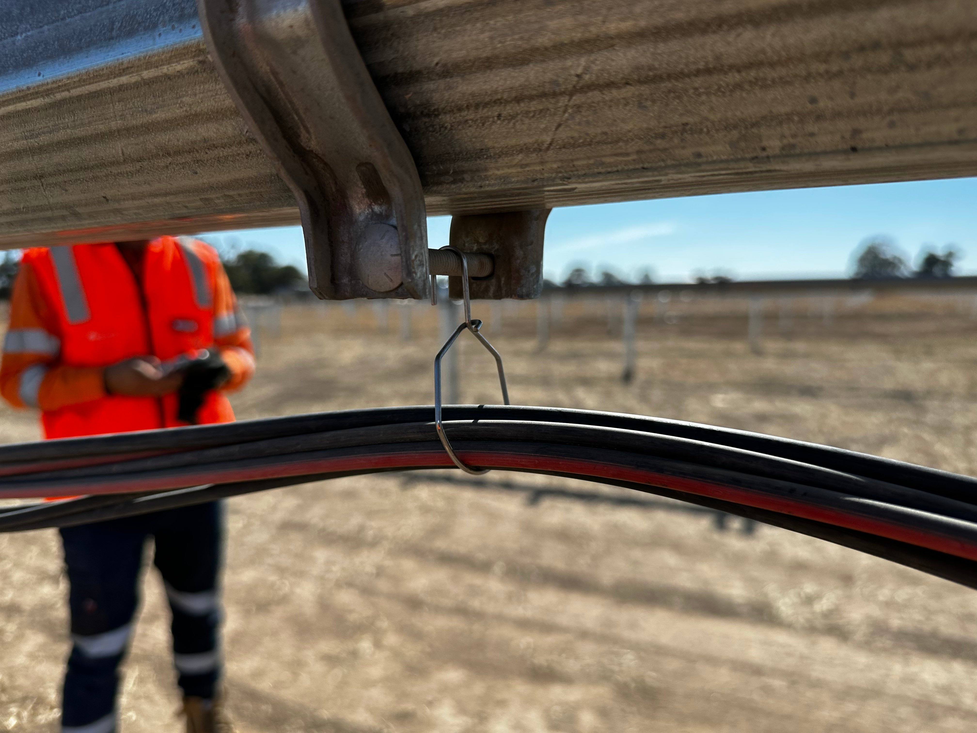 Installer securing string cable into ECLIPZ hanger by hand without tools during solar farm tracker assembly